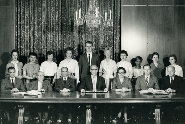 <p>Earliest staff photograph, Hunt Botanical Library (now Hunt Institute for Botanical Documentation), conference room (now gallery), 1962, photograph by an unknown photographer, HI Archives Institutional Archives collection. <em>Standing, from left</em>: Freda K. Harter (administrative secretary, 1962–1963), Olga P. Macek (bookkeeper, 1961–1962), Irene E. Kueshner (cataloguing assistant, 1961–1962), Mary Kalberer (student assistant, 1962–1963), Robert Pfaller (student assistant, 1962–1966), Joan L. Sabo (bindery assistant, 1962–1963), Jeane L. Criss, (office assistant, 1961–1962; cataloguing assistant, 1962–1965), Beatrice Johnson (housekeeper, 1961–1968), Flavia Zortea (assistant bookbinder, 1961–1970), Penelope G. Williams (bindery assistant, 1961–1964). <em>Seated, from left</em>: John V. Brindle (1911–1991; curator of art, 1961–1982), Thomas W. Patterson (1905–1972; bookbinder, 1961–1972), Ian MacPhail (1923–2014; bibliographer, 1961–1964), George H. M. Lawrence (1910–1978; director, 1960–1970), Helen Becker (cataloguer, 1961–1962), Willem D. Margadant (1916–1997; assistant librarian, 1962–1970), James D. Van Trump (1908–1995; bibliographic assistant, 1962–1963).</p>